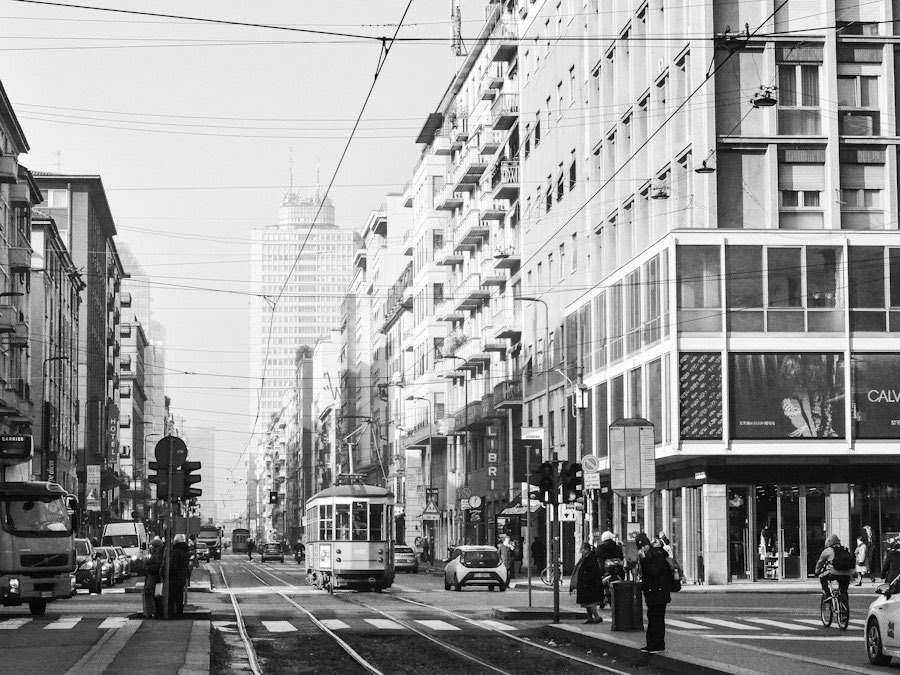 A Milan street with shops and a tram